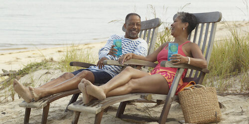 Senior couple lounging on beach with drinks